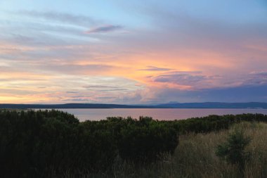 Kırsal kesimdeki dramatik gökyüzünde canlı bulutlarla renkli bir gün batımı.