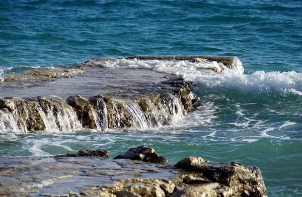 背景に深い青色の海と石のサンゴ礁の上に流れる波の海水 — ストック写真