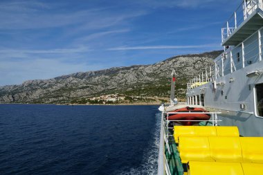 Güzel bir yaz gününde kıyıdan denize sürüklenen feribotun yan görüntüsü.