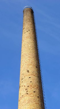Sarı tuğlalardan yapılmış eski bir fabrikanın bacası.