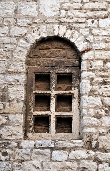Decorative antique stone window built into the stone wall of the old basilica