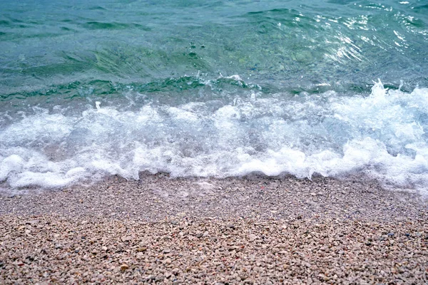 海岸の小石を飛び散らせる大きな白い泡の波と海の潮の空中ビュー — ストック写真