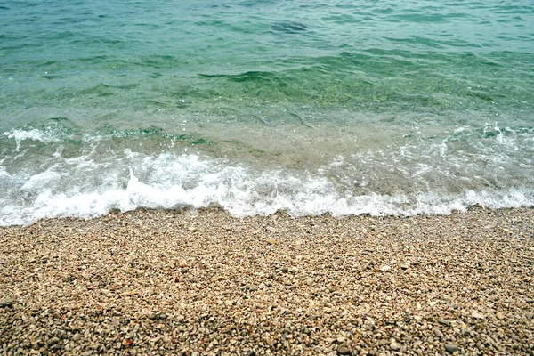 多风的日子里 蓝绿色海水在卵石海滩上方的自然背景 — 图库照片