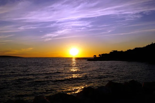 Bluish sky with white veiled clouds above beautiful seascape at sunset and silhouette of the coast in the summer