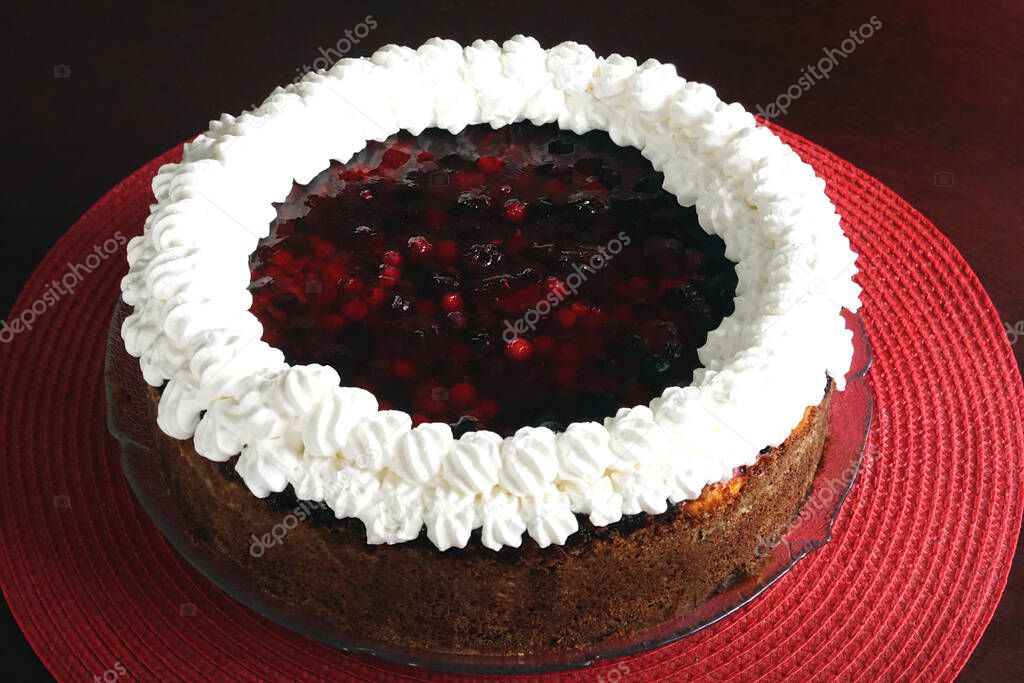 Homemade cake with fresh gelled berry fruit and natural whipped cream on a red background