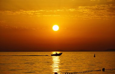 Güzel doğa arka planı, güzel turuncu günbatımında deniz yüzeyinin üstünde parlayan güneş topu.