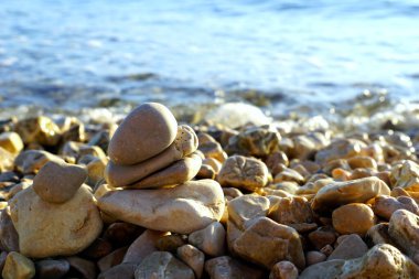 Çakıl taşları, çakıl taşı plajına istiflenmiş yaz günbatımında güneş tarafından aydınlatılmış.