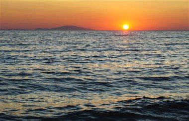 Sakin ve güzel deniz manzaralı arka plan. Mavi deniz yüzeyinde turuncu günbatımı var.