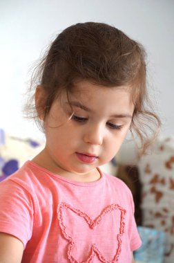 Oyuna odaklanmış dört yaşındaki bir kızın ciddi bir yüzü.
