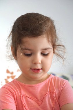 Güzel, koyu renk saçlı, dört yaşında bir kız aşağı bakar ve düşünür.