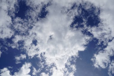 Yuvarlak beyaz kümülüs bulutu, ortasında küçük bir delik bulutlu bir günde mavi gökyüzünde.