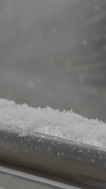 Balkon korkuluklarında beyaz kar taneleri olan bir evin penceresinden kaydedilen kar yağışı