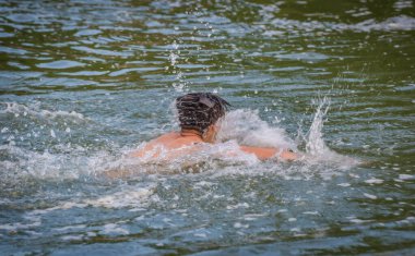 Adam bir dağ nehrinde sürünüyor.