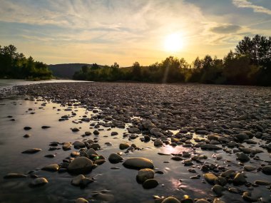 Bir yaz akşamı akan bir dağ nehrinin manzarası.