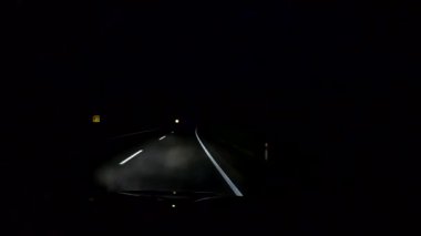 Dağlık bir bölgede gece yolunda giden bir SUV.
