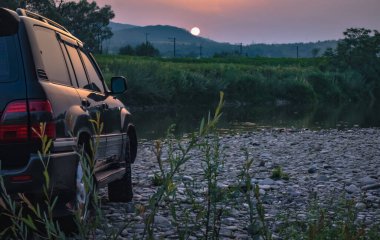 SUV bir dağ nehri üzerinde seyahat eder.