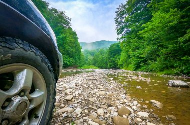 SUV bir dağ nehri üzerinde seyahat eder.