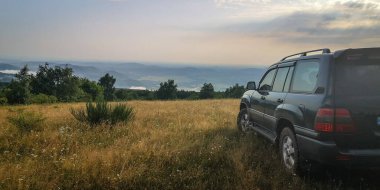 SUV bir yaz akşamı vadiye bakan dağlık bir alanda seyahat eder.