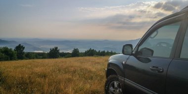 SUV bir yaz akşamı vadiye bakan dağlık bir alanda seyahat eder.