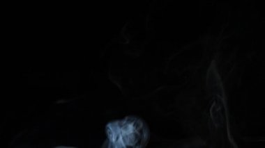 Beautiful movement of smoke in a beam of light on a dark background