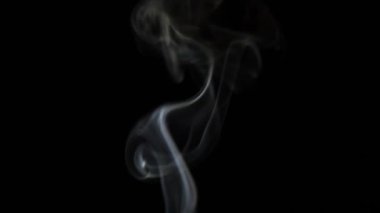 Beautiful movement of smoke in a beam of light on a dark background
