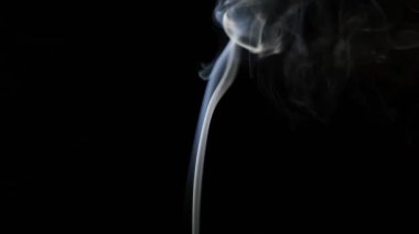 Beautiful movement of smoke in a beam of light on a dark background