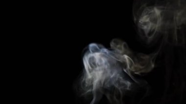 Beautiful movement of smoke in a beam of light on a dark background