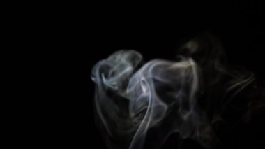 Beautiful movement of smoke in a beam of light on a dark background