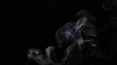 Beautiful movement of smoke in a beam of light on a dark background