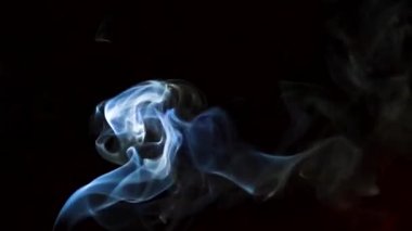 Beautiful movement of smoke in a beam of light on a dark background