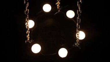 Zincire vurulmuş mumlarla çevrili aptal insan kafatası.