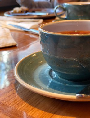 Bir fincan taze demlenmiş çay, ılık yumuşak ışık, koyu arka plan. Kafede.