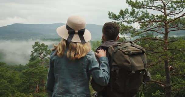 Een vrouw en een man staan op een klif en kijken naar de natuur. Wandelen in de bergen. 4K DCI — Stockvideo