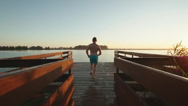 A young man is jumping into the lake in the style of a bomb. Rest on the lake. Sunset. 4K — Stock Video