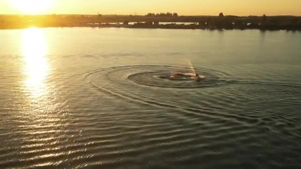 Люди на водном скутере кружат над водой. Закат на заднем плане. Стрельба из беспилотника. 4K — стоковое видео