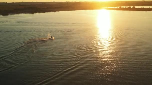 La gente en un scooter de agua está haciendo giros en el agua. Puesta de sol en el fondo. Disparando desde un dron. 4K — Vídeos de Stock