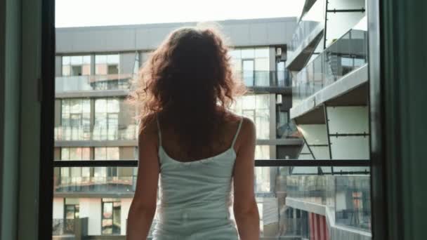 Młoda piękna kobieta wychodzi na balkon swojego mieszkania. 4K — Wideo stockowe