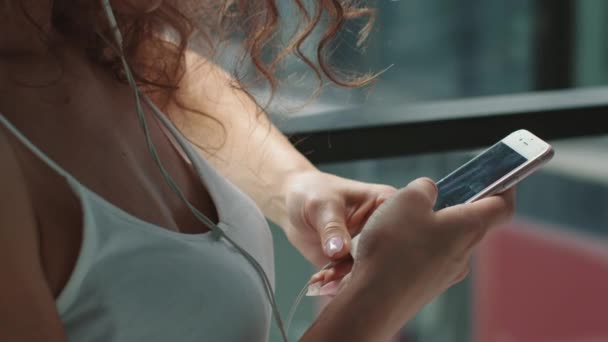Κοντινό πλάνο. Μια νεαρή γυναίκα στέλνει μηνύματα στο κινητό της. Ακούει μουσική και στέκεται στο μπαλκόνι. 4K — Αρχείο Βίντεο
