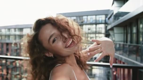 Młoda kobieta kręci film na przedniej kamerze smartfona. Patrzy w kamerę i uśmiecha się. 4K — Wideo stockowe