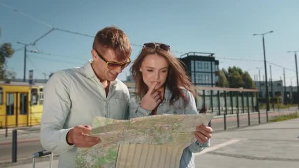 Mężczyzna i kobieta patrzą na mapę miasta. Wyznaczają trasę. Stary tramwaj jedzie w tle. 4K — Wideo stockowe
