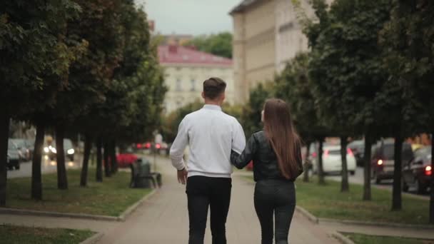 한 남자와 한 여자가 공원을 걷고 있습니다. 그들은 말하고 손을 잡고 있다. 뒤에서 총을 쐈어요. 4K — 비디오