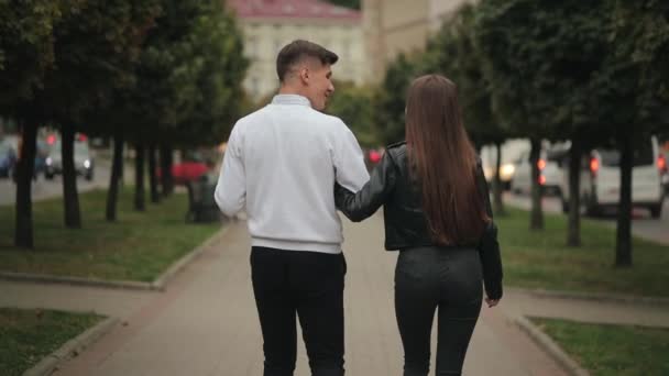 En man och en kvinna går i parken. De pratar och håller varandra i handen. 4K — Stockvideo