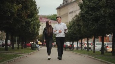 Bir adam ve bir kadın parkta yürüyorlar. Konuşuyorlar ve gülümsüyorlar. 4K