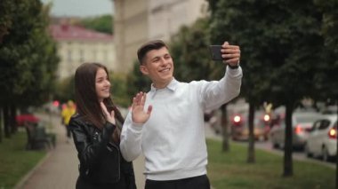 Bir erkek ve bir kadın selfie çekiyor. Gülümsüyorlar ve şehirde dolaşıyorlar. 4K