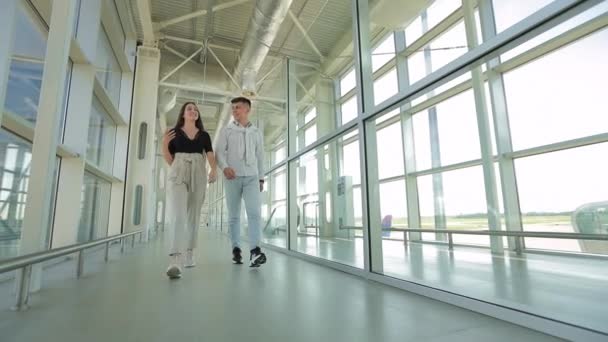 若い女性と男が話していて、空港を歩いている。4K — ストック動画