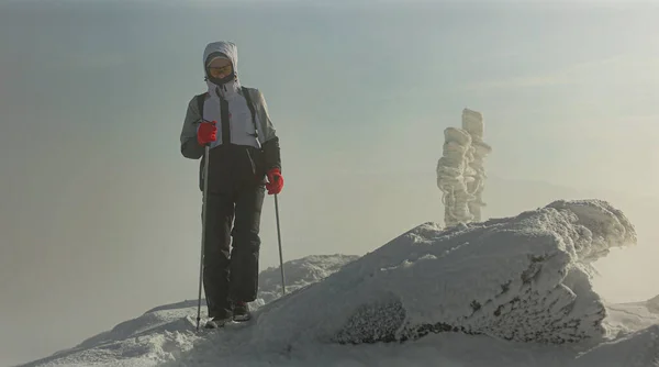 Uma jovem está andando no topo de uma montanha coberta de neve. Há grandes montes de neve ao lado dela. Há vento forte e neve. Monte Pikui. — Fotografia de Stock