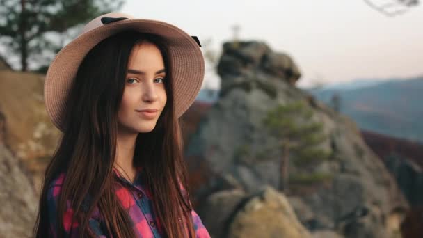 Portrait d'une jeune femme. Elle regarde la caméra et sourit. Paysage de montagne en arrière-plan. 4K — Video