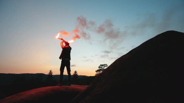 一个人站在悬崖边上，在夜里挥着两枚照明弹。在山上生存。在山上远足。4K — 图库视频影像