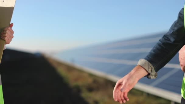 Een close-up opname. Ingenieurs schudden elkaar de hand. Zonnepanelen op de achtergrond. 4K — Stockvideo