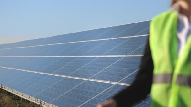 Vedle solárních panelů stojí ženský inženýr. Zvedla žárovku a drží ji v ruce. Natáčení zblízka. 4K — Stock video